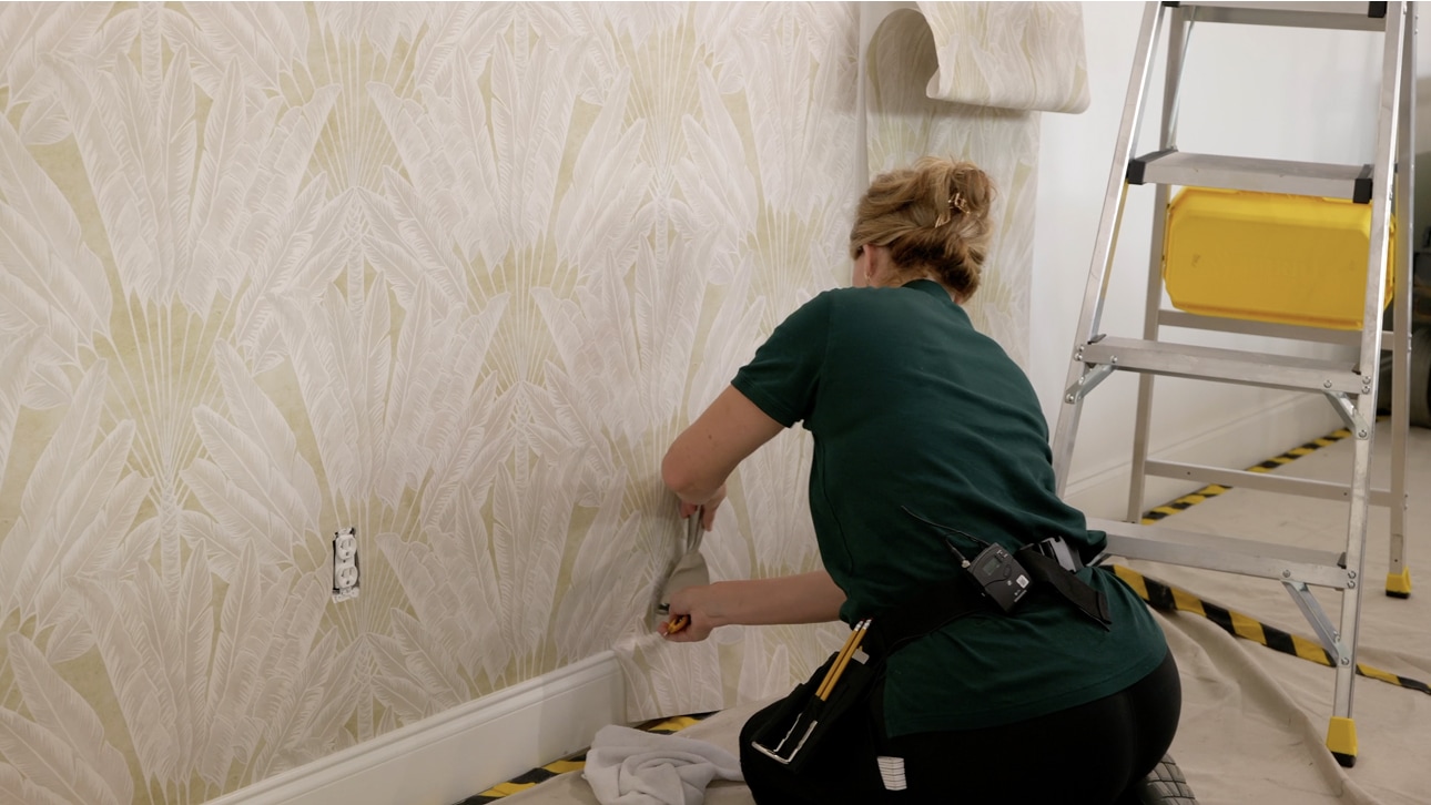 Professional wallpaper installer working on a pale patterned wall